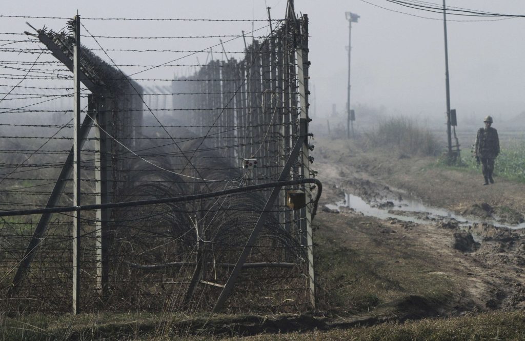 An Indian BSF soldier patrols near the fenced border with Pakistan amid fog in Suchetgarh
